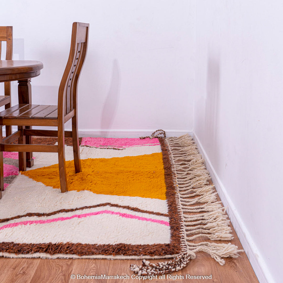 Handmade colorful Moroccan rug with pink, yellow, brown, and green geometric patterns on white wool