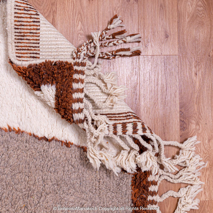 Handmade colorful Moroccan rug with pink, yellow, brown, and green geometric patterns on white wool