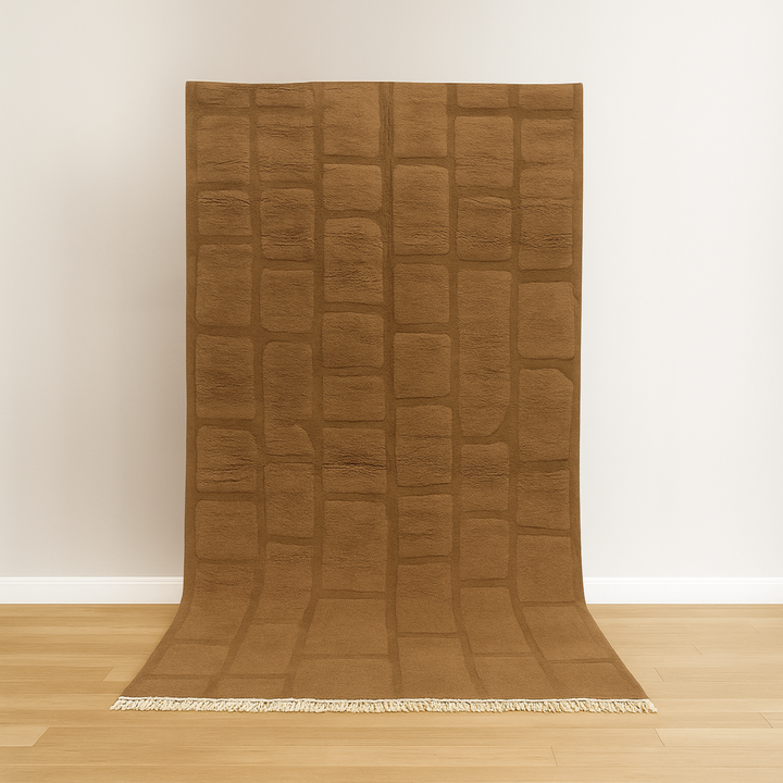 Brown textured rug on a wooden floor with a white wall background