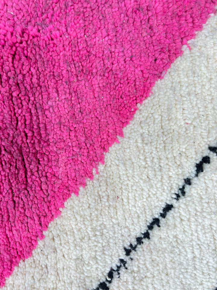 Round Moroccan wool rug with geometric pink, black, and white sections and a central diamond motif.