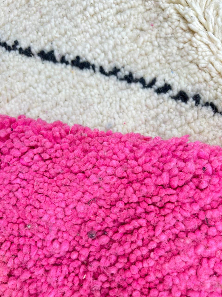 Round Moroccan wool rug with geometric pink, black, and white sections and a central diamond motif.