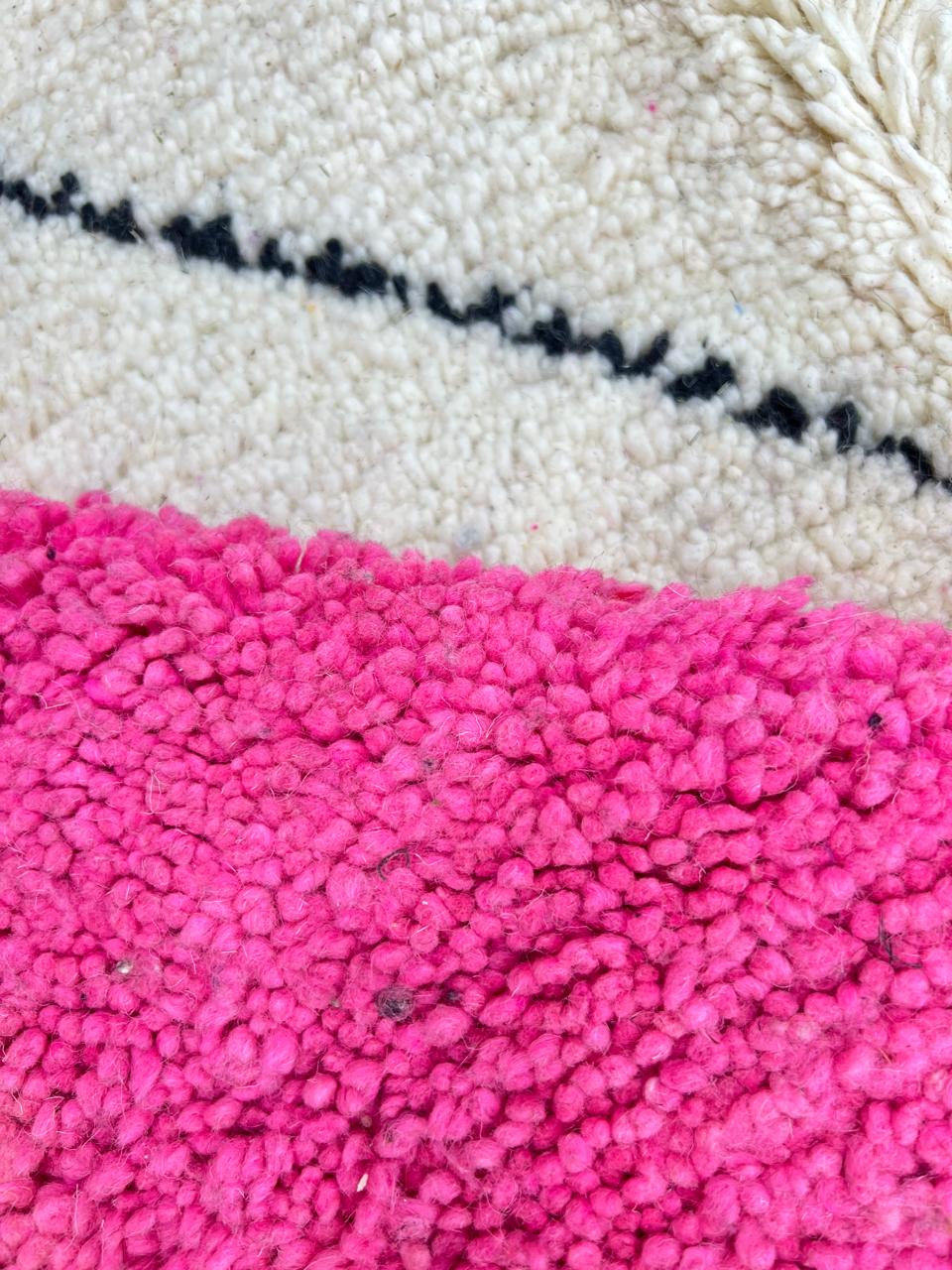 Round Moroccan wool rug with geometric pink, black, and white sections and a central diamond motif.