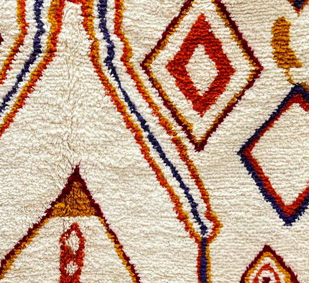 Handmade Moroccan wool runner rug with geometric Berber motifs in terracotta, mustard, blue, and purple on a cream background