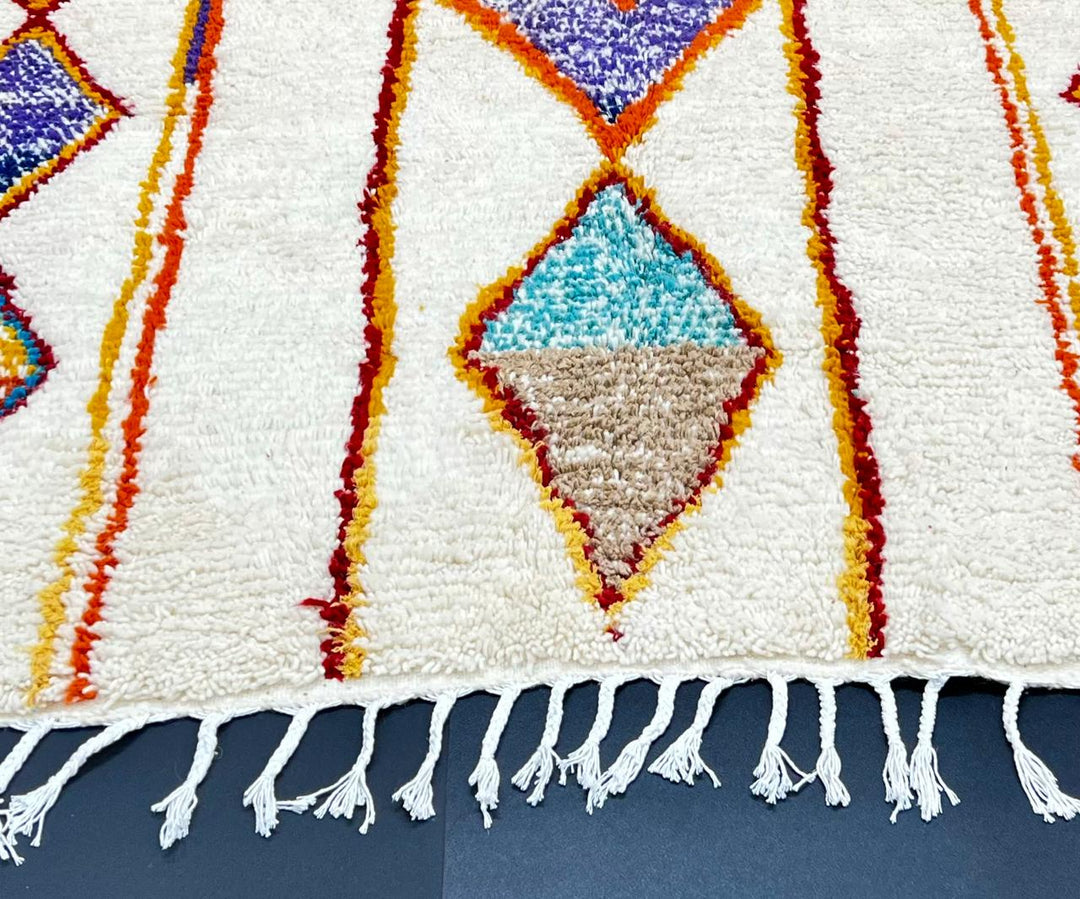 Handmade Moroccan wool runner rug with geometric Berber motifs in terracotta, mustard, blue, and purple on a cream background