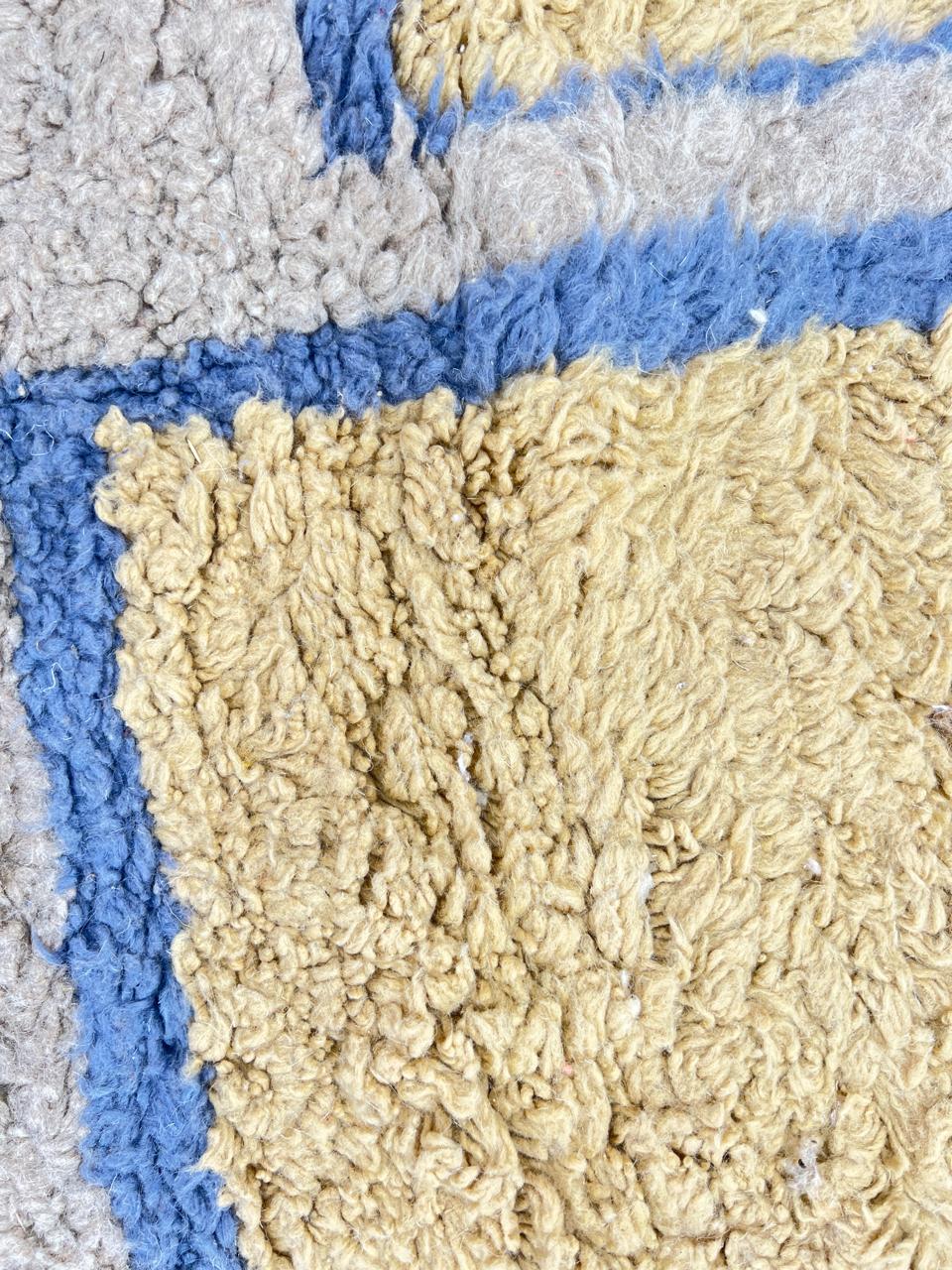 Golden Moroccan wool runner rug with blue geometric border and neutral background, handmade by Berber artisans