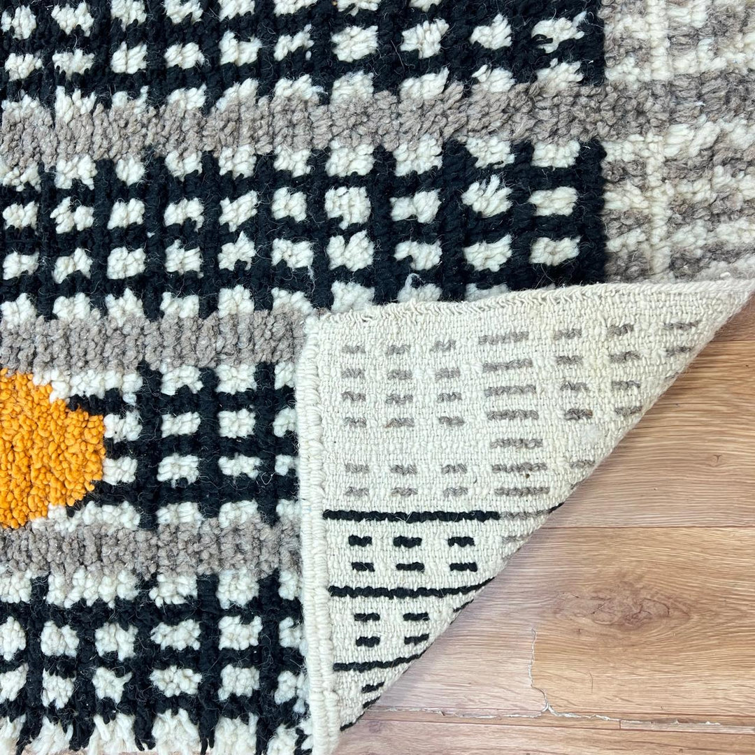 Handmade Moroccan wool rug with black grid and amber dot design. Soft plush texture, modern style, and artisan crafted.