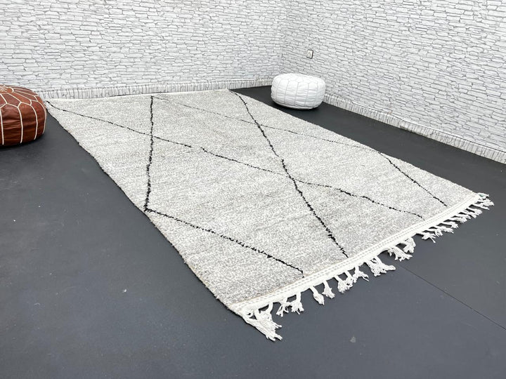 Handwoven gray Moroccan wool rug with black diamond pattern and fringes, handmade by Berber women in the Atlas Mountains