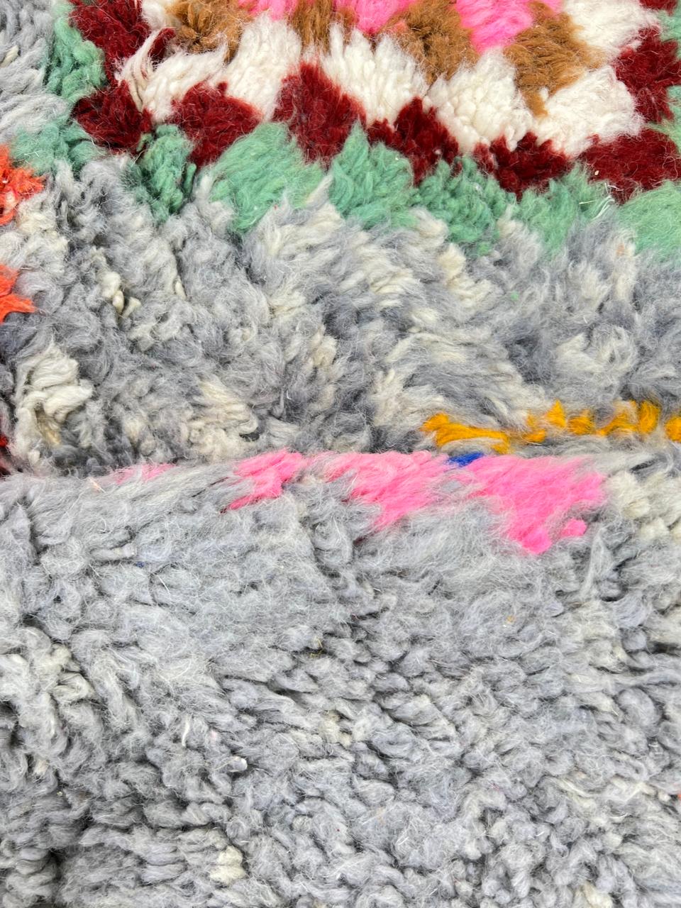 Round grey Moroccan wool rug with colorful Berber diamond motifs and tribal geometric patterns.