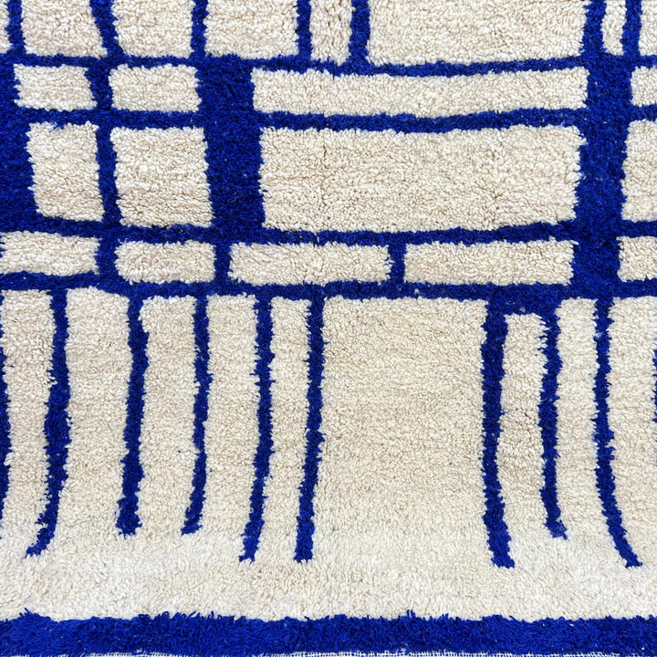 Handmade round Moroccan wool rug with blue Berber geometric pattern on ivory natural wool background