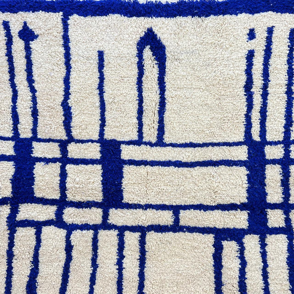 Handmade round Moroccan wool rug with blue Berber geometric pattern on ivory natural wool background