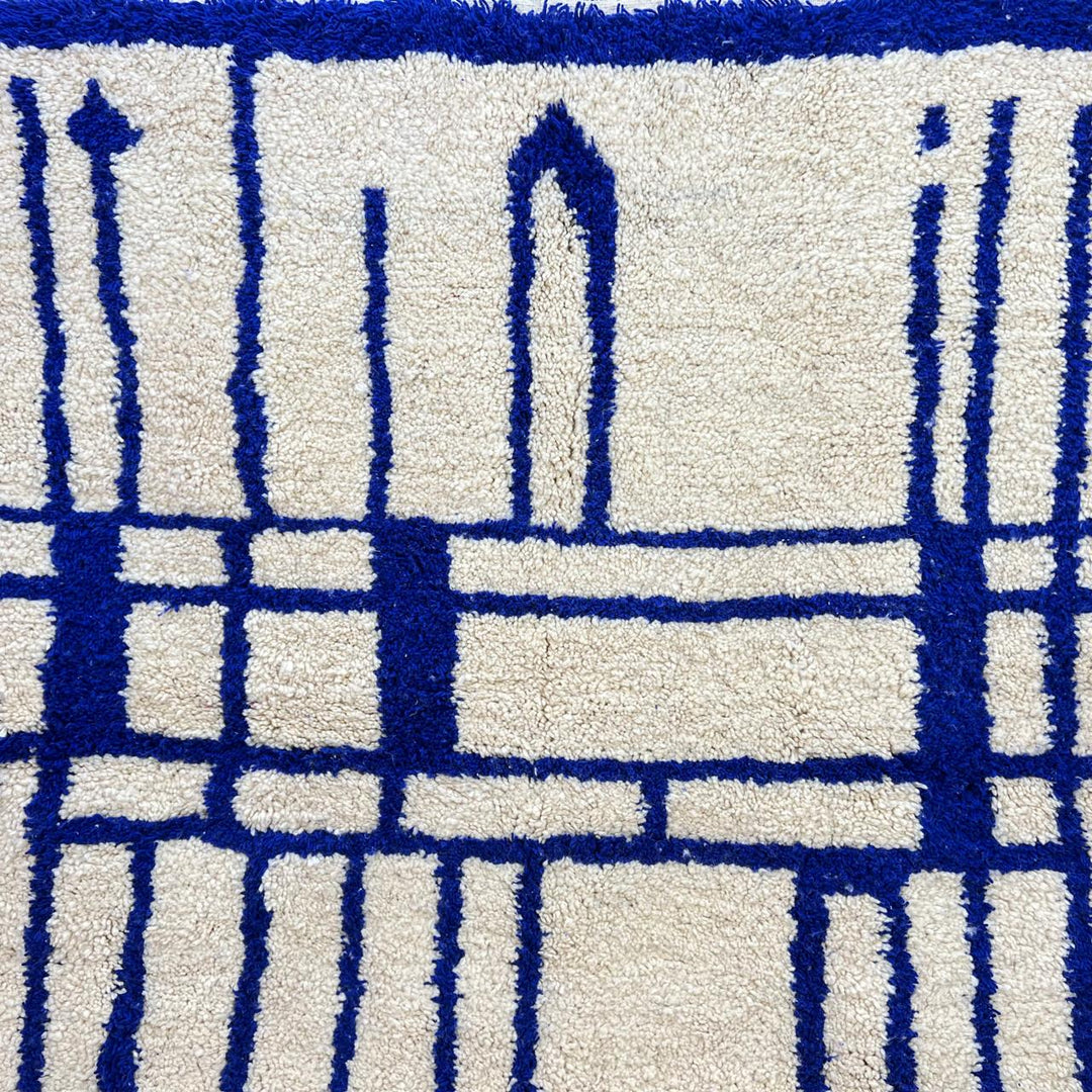 Handmade round Moroccan wool rug with blue Berber geometric pattern on ivory natural wool background