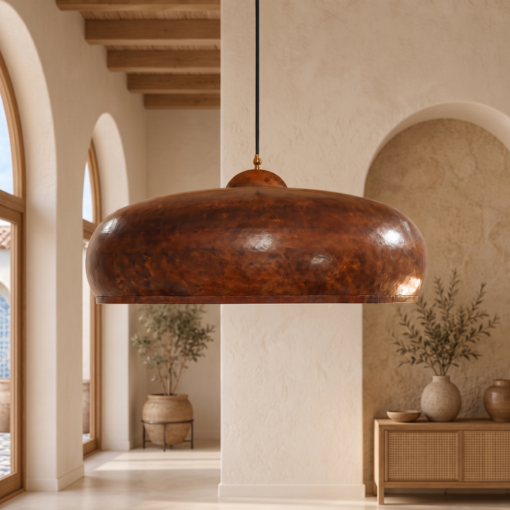 Handmade hammered copper pendant light with a wide Moroccan dome design, displayed in a modern luxury living room.