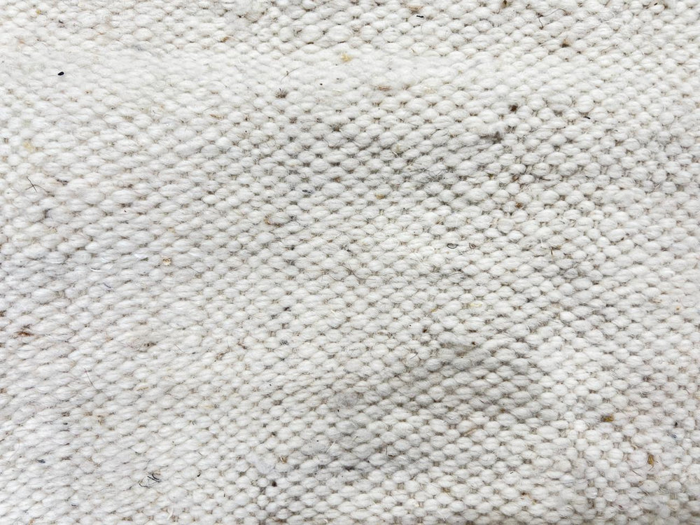 Handmade Moroccan flatweave kilim rug with soft neutral tones and subtle geometric shapes, woven from natural wool.