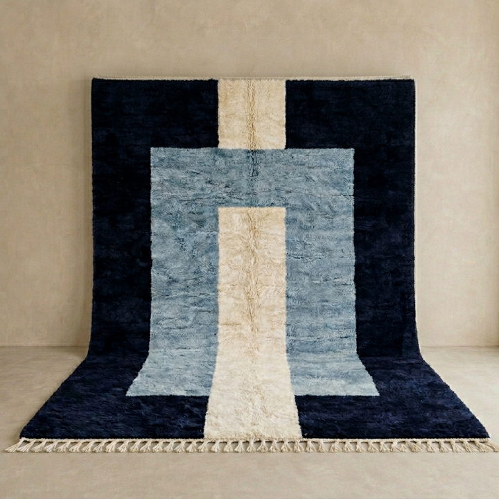 Handmade modern Moroccan wool rug featuring black, blue, and cream geometric block design with soft texture and fringe tassels.