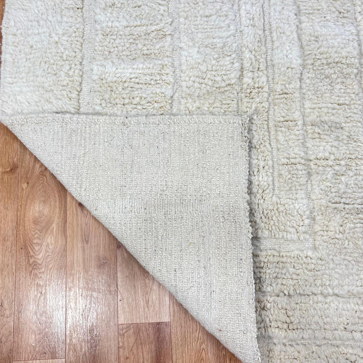 Handmade Moroccan wool runner rug in cream with raised carved geometric design and fringed ends
