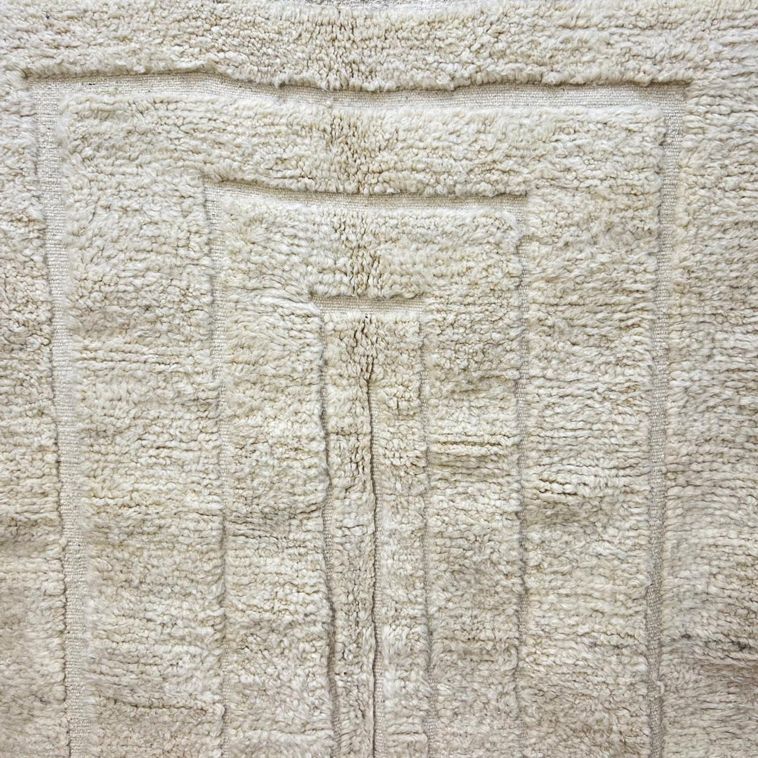 Handmade Moroccan wool runner rug in cream with raised carved geometric design and fringed ends