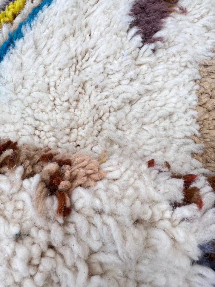 Handmade round Moroccan wool rug in white and brown with colorful Berber pattern