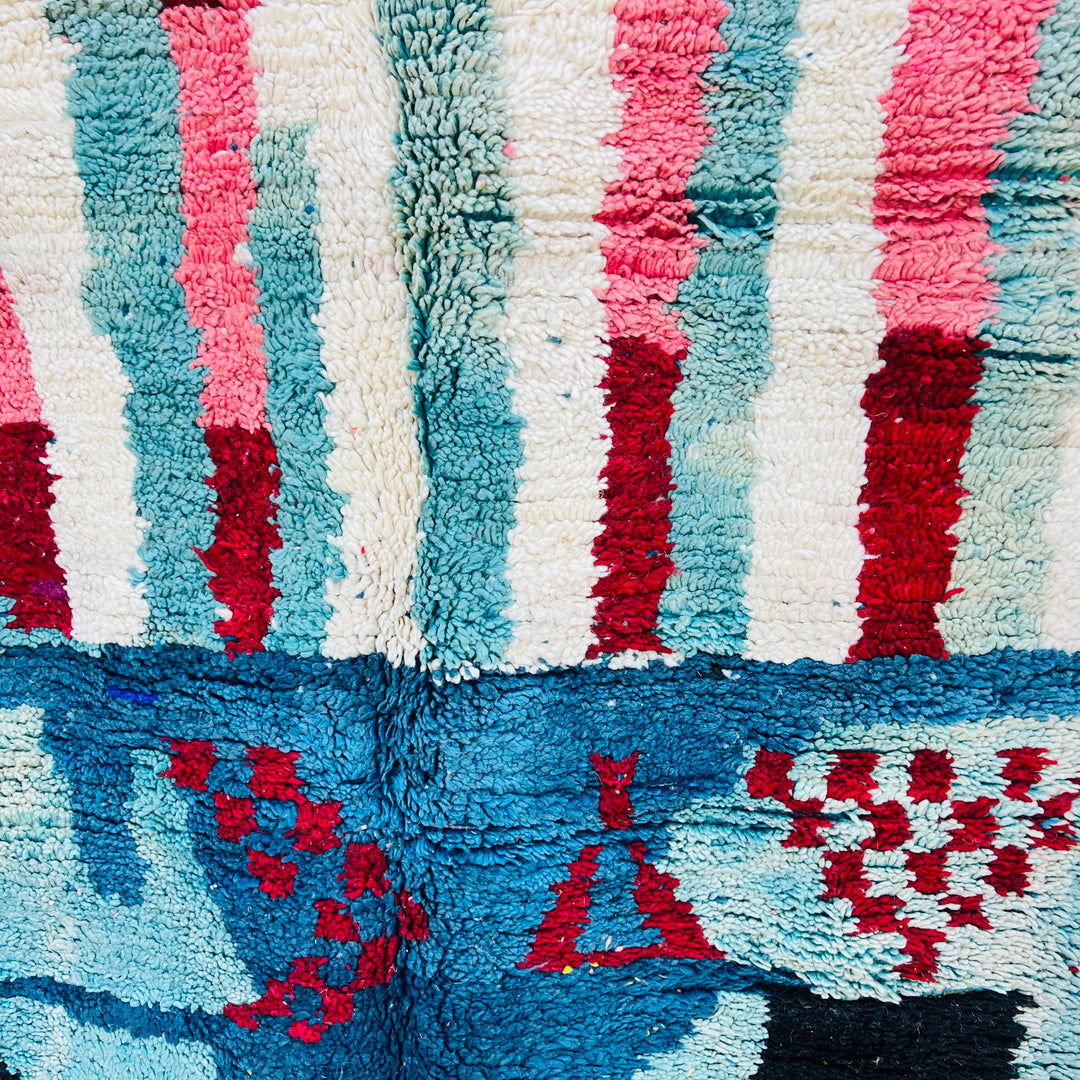 Vintage Moroccan abstract rug with vibrant red, blue, and pink motifs, handwoven in wool. Perfect for adding boho flair to your space.