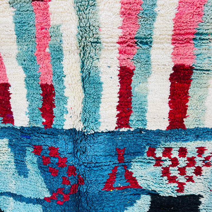 Vintage Moroccan abstract rug with vibrant red, blue, and pink motifs, handwoven in wool. Perfect for adding boho flair to your space.