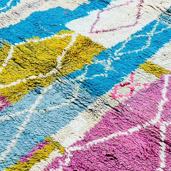 Abstract vintage Moroccan Berber rug with pink, blue, and mustard diamond motifs, handwoven from natural wool.