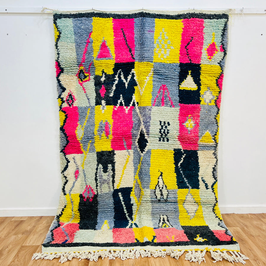 Vintage Moroccan wool rug 8x5 ft with bold tribal colors, handwoven Berber area rug featuring pink, yellow, black, and blue patterns.