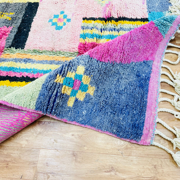 Vintage Moroccan Berber rug featuring colorful patchwork design in wool, with vibrant pinks, blues, and yellows. 8.7x5 ft area rug.