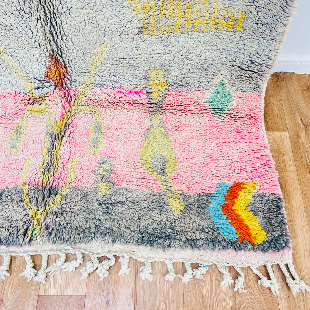 Vintage Moroccan rug 8.5x5.1 ft with tribal symbols, colorful diamonds, and soft pastel tones, handmade wool carpet on wooden floor.