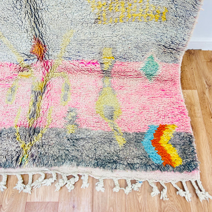 Vintage Moroccan rug 8.5x5.1 ft with tribal symbols, colorful diamonds, and soft pastel tones, handmade wool carpet on wooden floor.