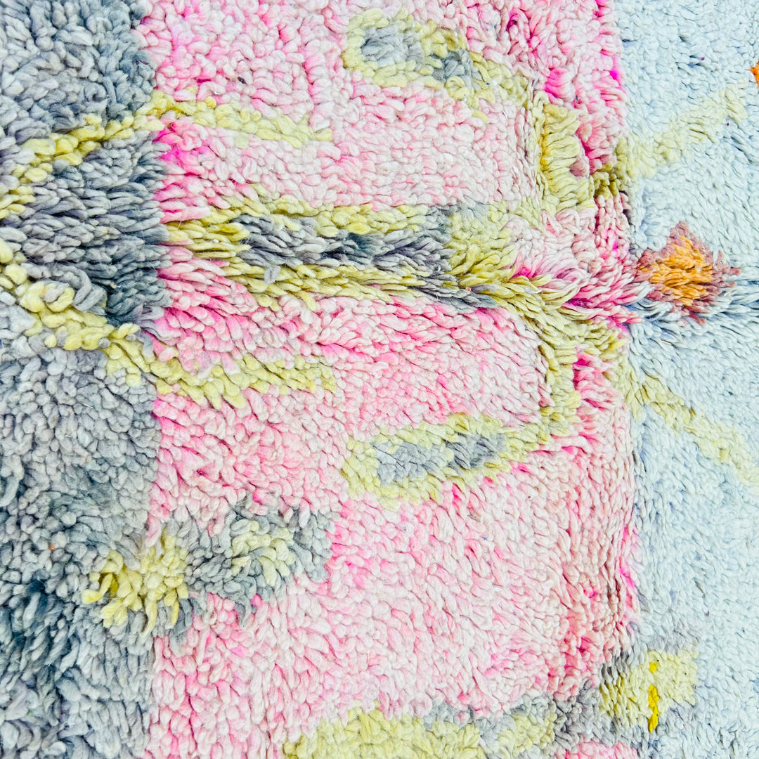 Close-up of a vintage Moroccan wool rug with colorful tribal patterns and soft pastel tones, handmade by Berber artisans.