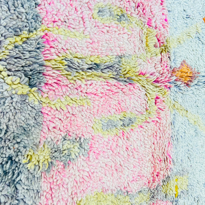 Close-up of a vintage Moroccan wool rug with colorful tribal patterns and soft pastel tones, handmade by Berber artisans.