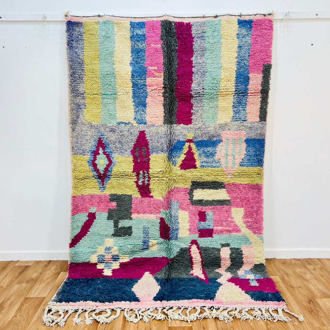 Colorful vintage Moroccan Berber rug with geometric patterns in pink, blue, yellow, and green stripes, handwoven 8x5 ft wool rug.
