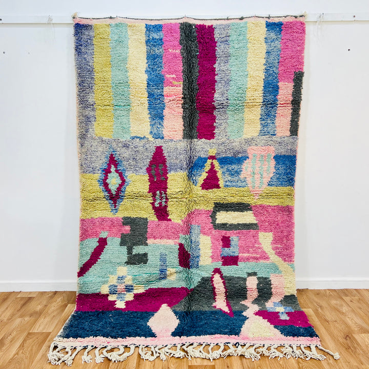 Colorful vintage Moroccan Berber rug with geometric patterns in pink, blue, yellow, and green stripes, handwoven 8x5 ft wool rug.