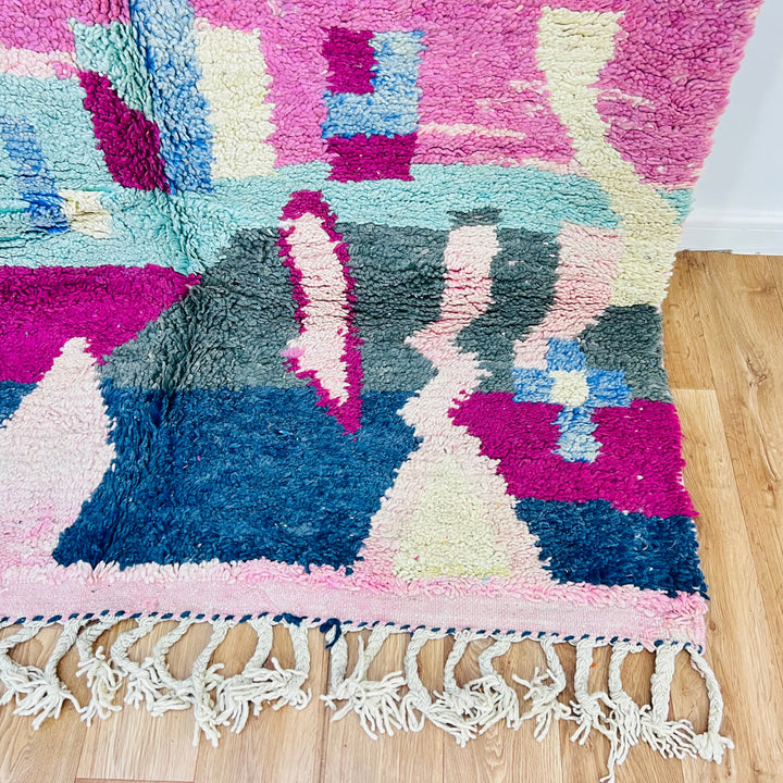 Colorful Moroccan Berber rug with geometric patterns in pink, blue, and green, 8x5 ft, handwoven with 100% wool, perfect for boho interiors.