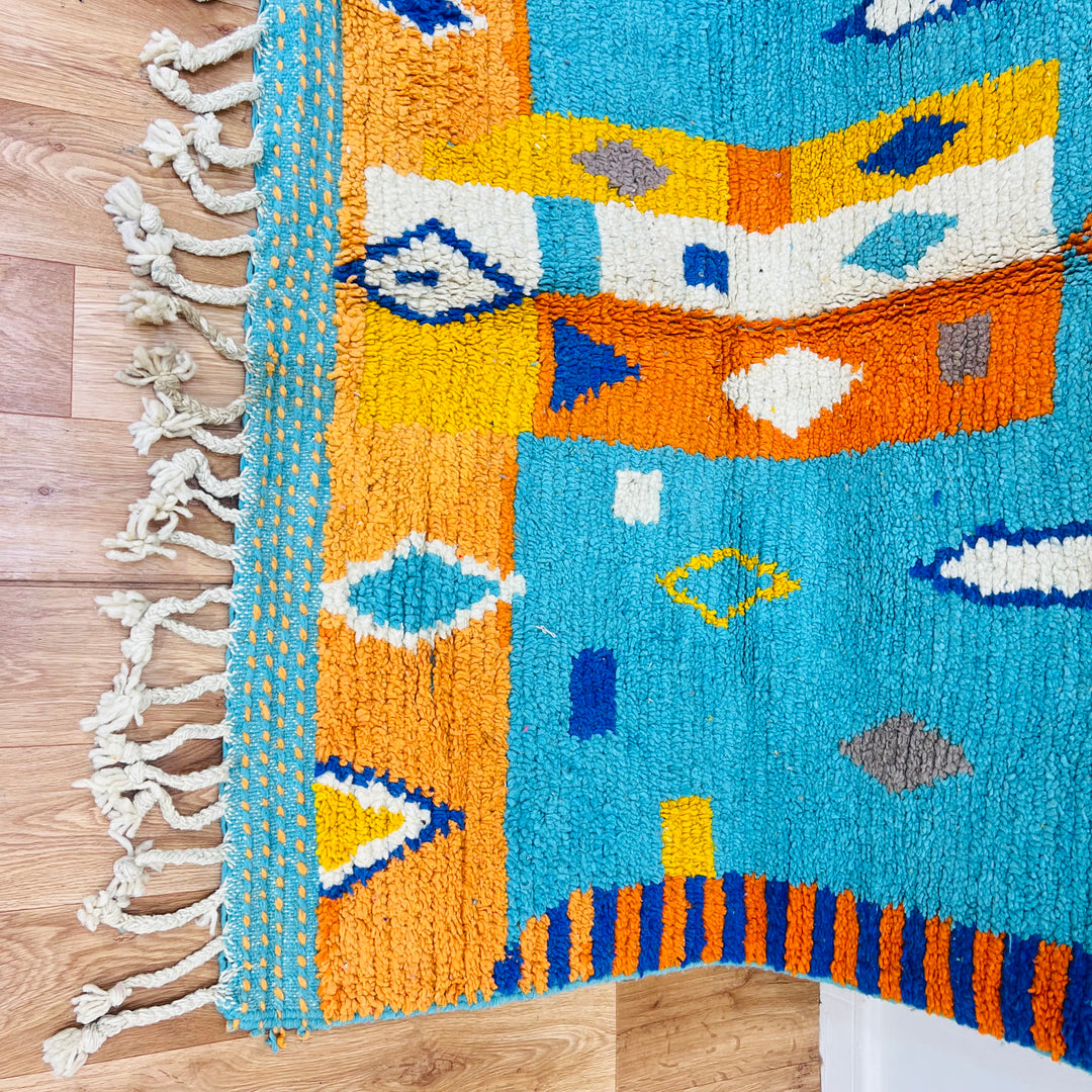 Handmade Moroccan Berber rug with turquoise and orange geometric patterns, crafted with 100% wool, vibrant and vintage style.
