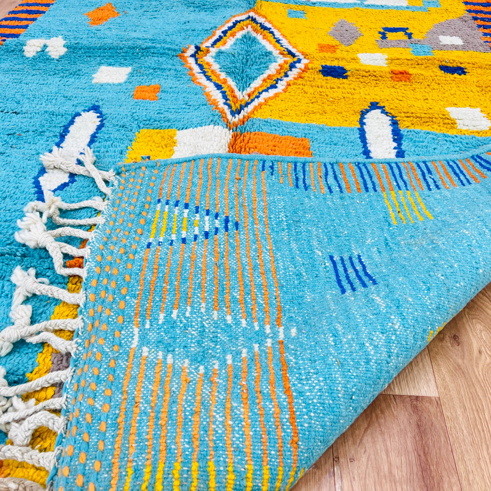 Blue and orange Moroccan Berber wool rug with geometric diamond pattern, handmade by artisans, perfect for boho or modern interiors.