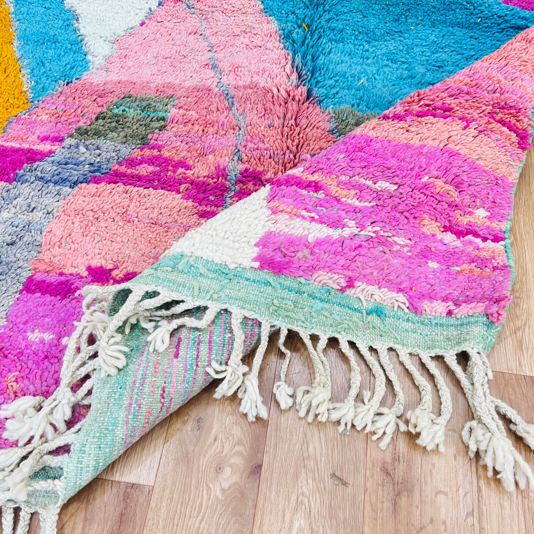 Color Block Moroccan Berber Rug with fuchsia, turquoise, and saffron designs, 100% wool, on wooden floor.