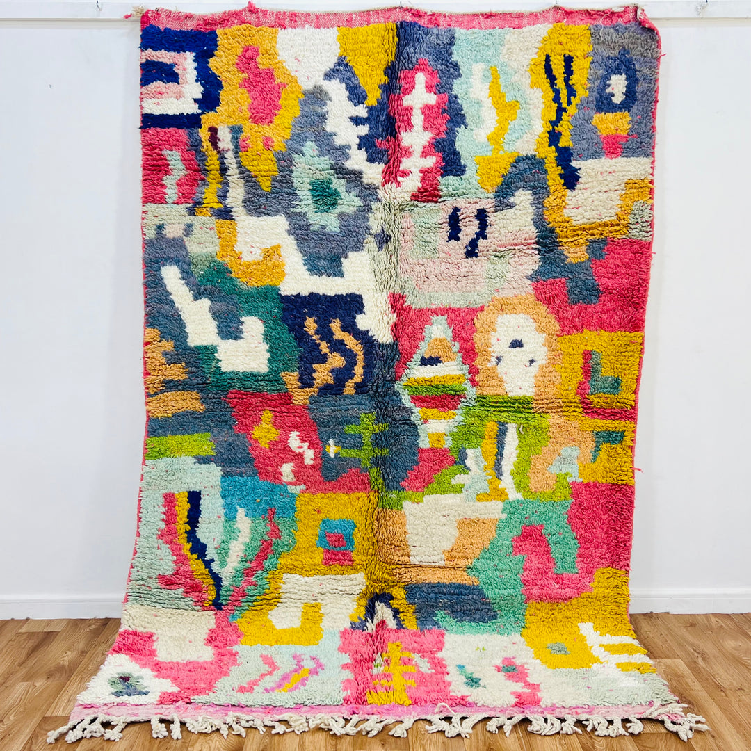 Colorful abstract Moroccan rug 7.9 x 5.4 ft with traditional Berber patterns in pink, blue, and yellow, handmade wool area rug.