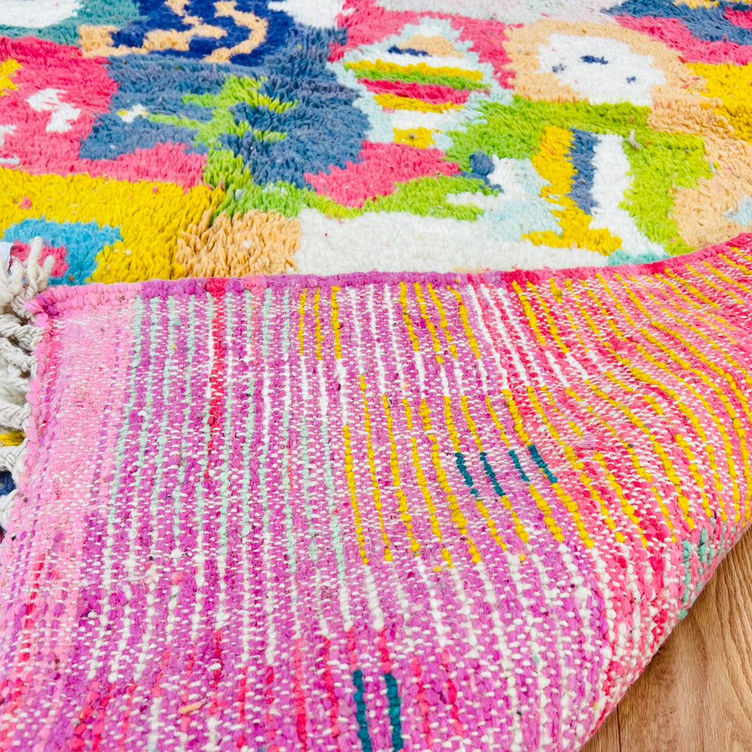 Colorful Moroccan wool rug with abstract pattern, showcasing pinks, blues, and greens, hand-knotted by artisans. Ideal for boho decor.