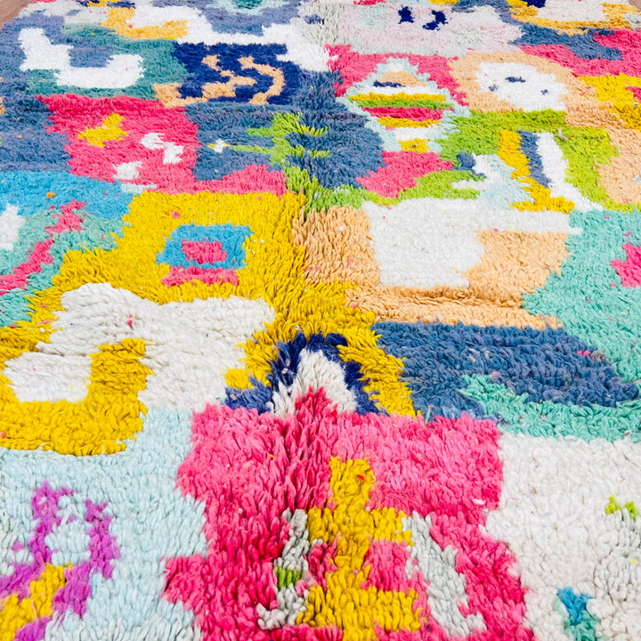 Colorful handmade Moroccan rug featuring vibrant abstract patterns in pink, blue, yellow, and green. Ideal for eclectic interiors.