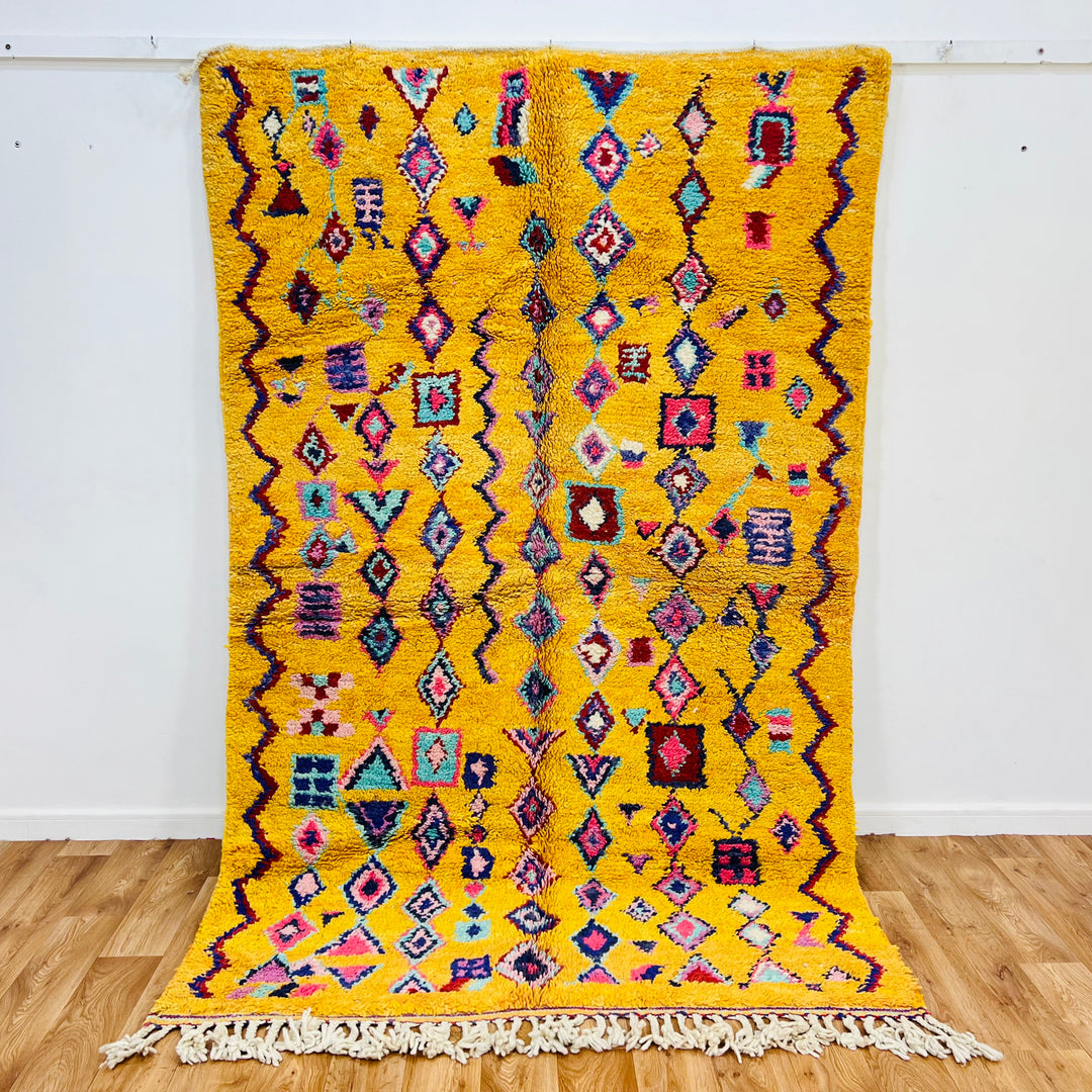 Yellow Moroccan Berber rug with colorful geometric patterns in pink, red, teal, and black, size 254 x 157 cm.