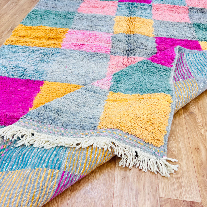 Vintage Moroccan rug with vibrant checkerboard pattern in pink, mustard, sage, and orange. Handwoven Berber art from the Atlas Mountains.