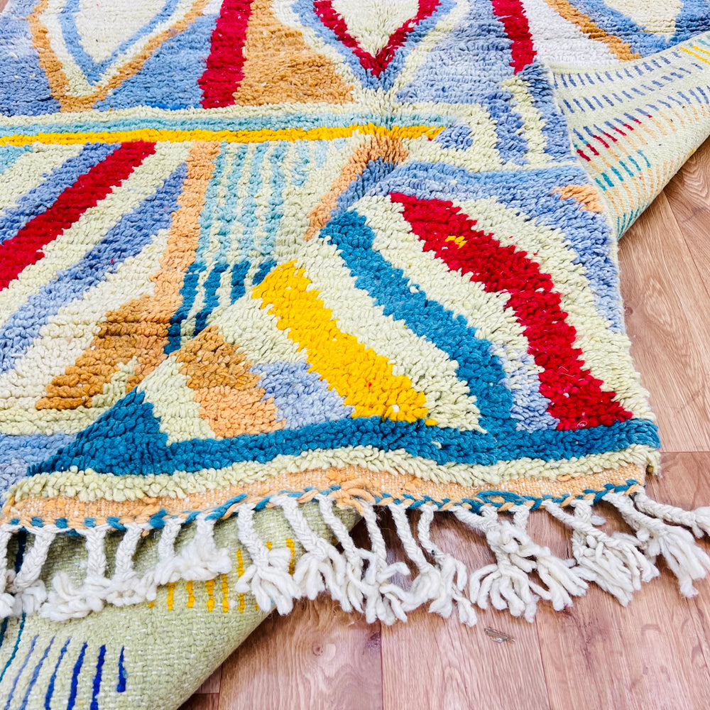 Vintage Moroccan Berber rug with colorful geometric patterns, handcrafted in the Atlas Mountains. Vibrant wool adds texture and warmth.