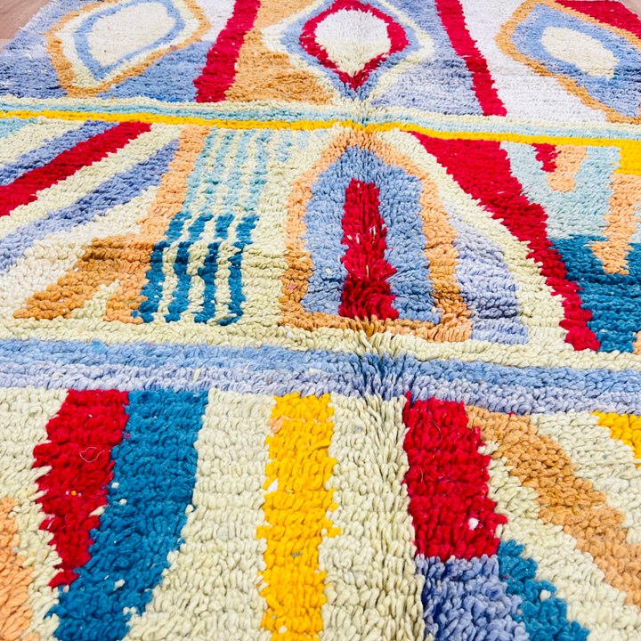 Colorful vintage Moroccan Berber rug with geometric patterns in red, blue, yellow, and cream. Handwoven wool rug from the Atlas Mountains.