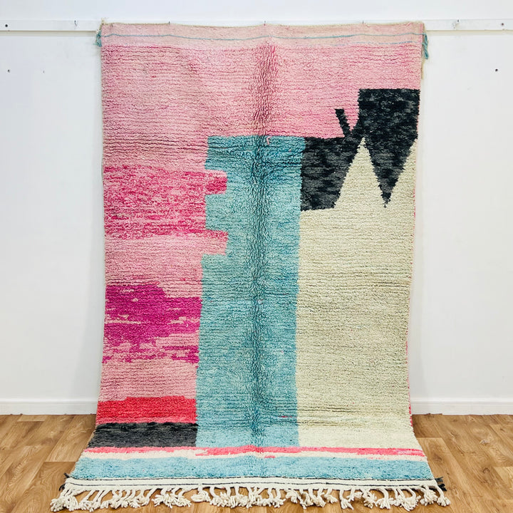 Handmade abstract pink Moroccan rug with aqua, ivory, and black shapes, 8x5 ft, vintage Berber design, wool material.