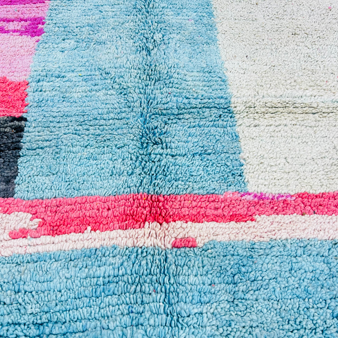 Close-up of a vintage abstract pink and blue Moroccan Berber rug made of natural wool, evoking mountain skylines and desert serenity.