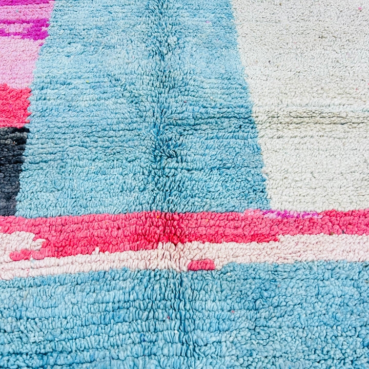 Close-up of a vintage abstract pink and blue Moroccan Berber rug made of natural wool, evoking mountain skylines and desert serenity.