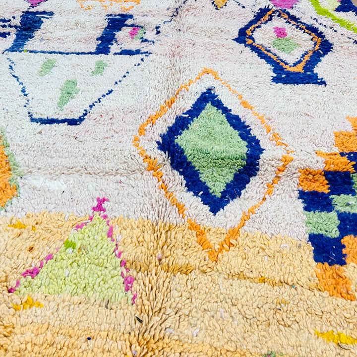 Colorful Moroccan rug with tribal diamond patterns and Berber symbols on a soft peach base, handwoven wool, measuring 248x150 cm.