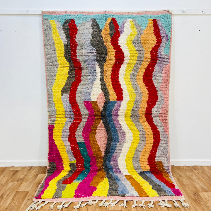 Vintage Moroccan rug with colorful wave pattern, 8.4×5.1 ft, handmade by Berber artisans, vibrant red, pink, teal, and mustard wool.