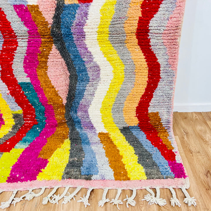 Colorful vintage Moroccan rug with wave pattern, made by Berber artisans. Features bold hues like red, pink, teal, and yellow.