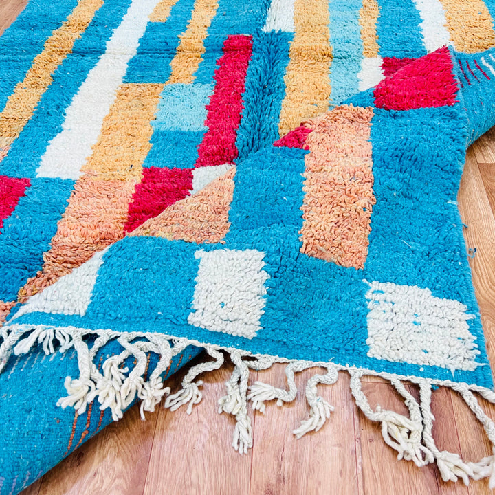 Vintage Moroccan rug in vibrant turquoise, ochre, red, and cream handcrafted by Berber artisans, featuring geometric patterns.